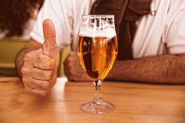 親指を立ててビールを飲む人の画像